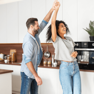 A happy couple dancing in their sparkling kitchen, freshly cleaned by Sparkclean Joy